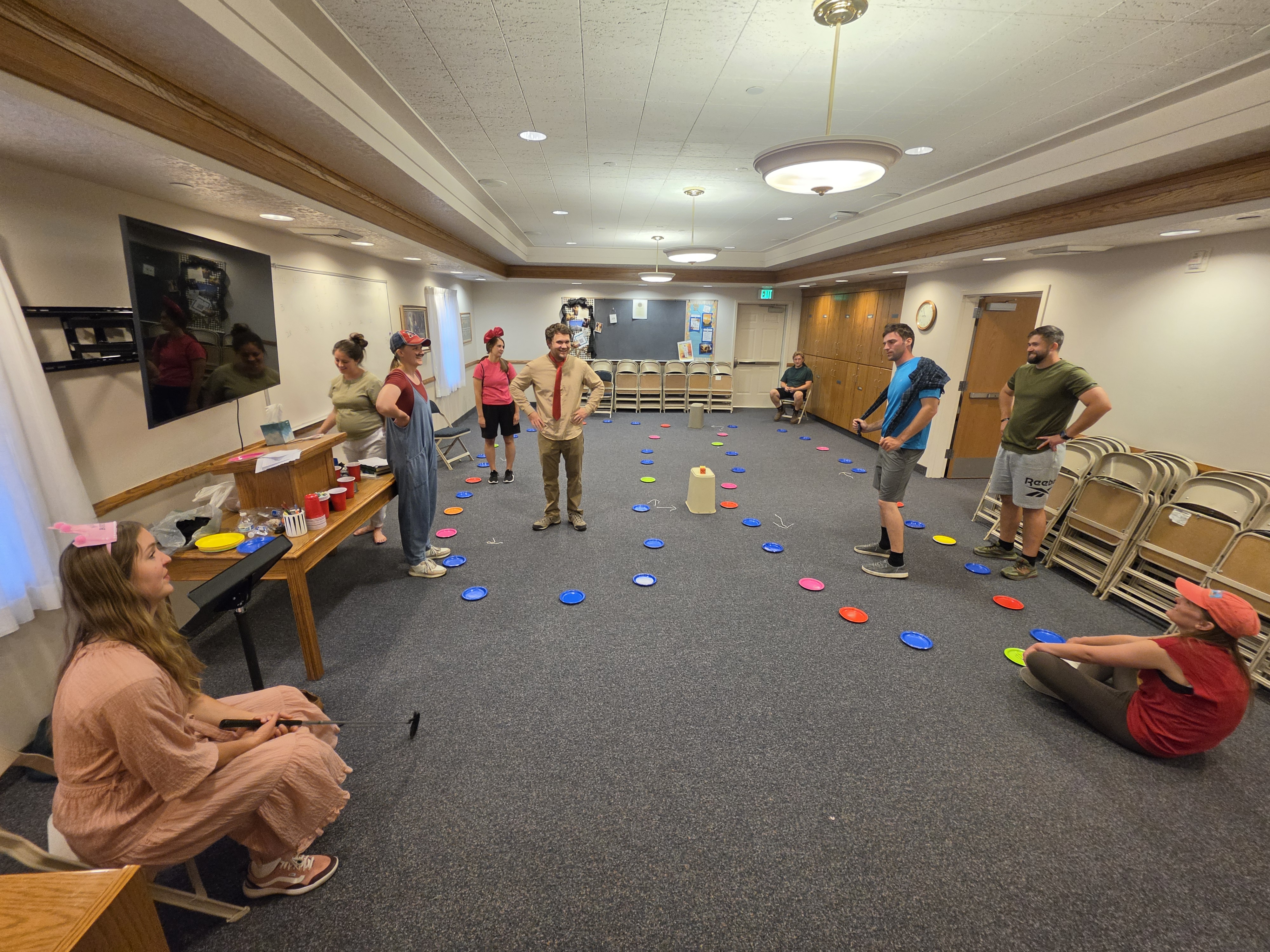 Group playing a hosted party game with colorful plates on the floor